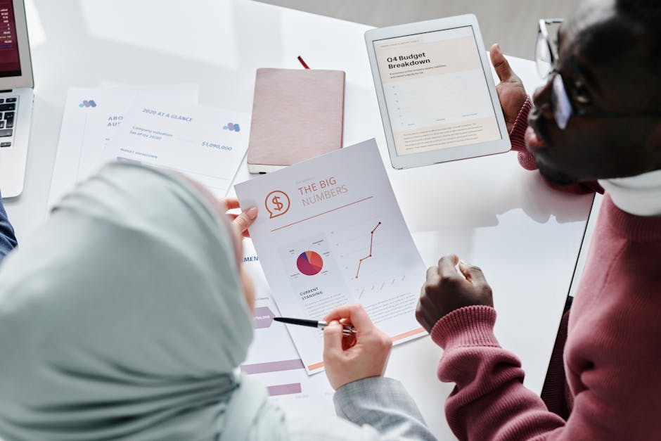 Two colleagues reviewing financial documents and graphs during an office meeting.
