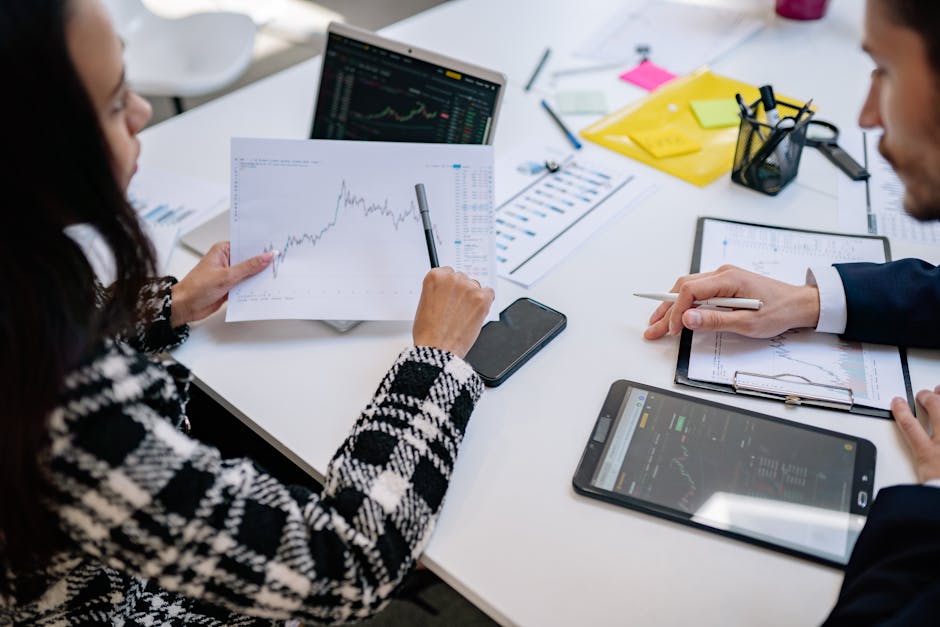 Two colleagues analyzing financial graphs during a business meeting in a modern office setting.